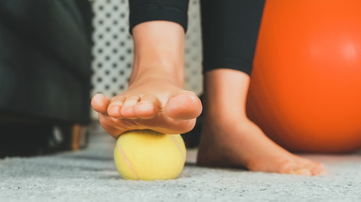 donna con pallina da tennis sotto il piede