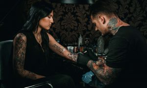 Tatuatore realizza tatuaggio sul polso a una ragazza